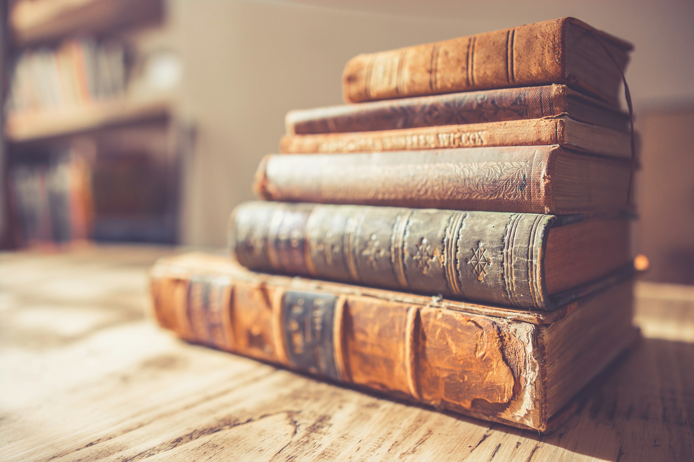 Antique leather-bound books stacked on a wooden table